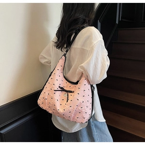 Dettaglio della borsa jacquard rosa con fiocchi neri e ciondolo a cuore argento