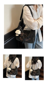 Detail view of black pleated tote bag with cute cat embroidery and white cloud pendant