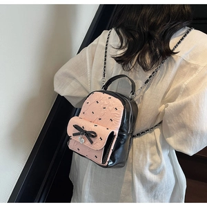 Pink seersucker mini backpack with black bow and chain strap worn by a model