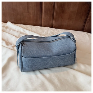 Detail view of blue denim pillow bag with silver zipper and thick shoulder strap