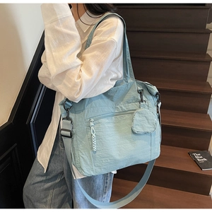 Detail of light blue nylon tote bag showing multiple pockets and adjustable shoulder strap