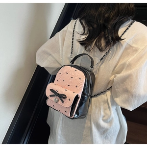 Detailed view of mini seersucker backpack with pink bow and heart pendant on model