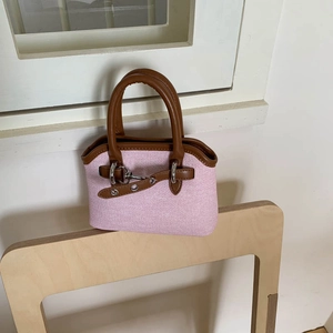 Detailed shot of pink woven fabric handbag with brown leather trim and metal lock charm