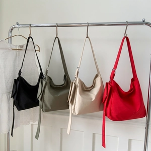 Dettaglio di quattro borse hobo in tela colorata nero verde beige e rosso su rack in metallo