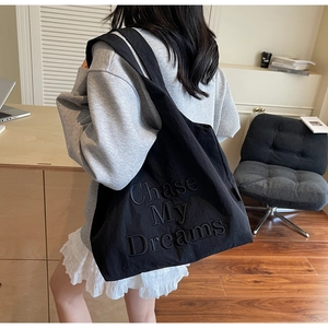 Gros plan détaillé de la broderie 3D Chase My Dreams sur un sac cabas en toile noire