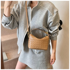 Detailed view of camel woven leather half-moon bag with elegant golden hardware