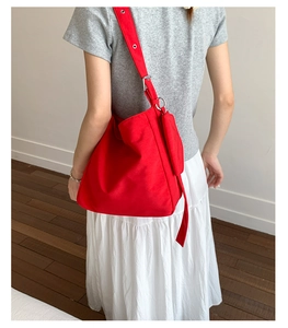 Detail of red canvas tote bag showing the durable texture and adjustable metal buckle