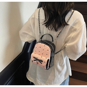 Mini seersucker backpack featuring pink textured panels and a delicate black bow on the back