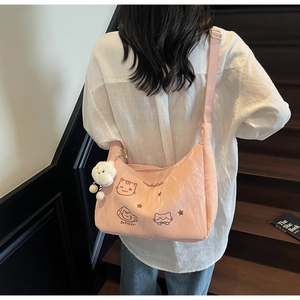 Close-up of pink nylon shoulder bag with cute cat embroidery and plush cloud charm