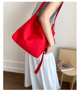 Detail of red high-capacity tote bag with wide strap and silver metal hardware