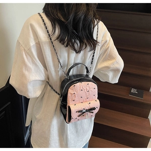 Detailed view of pink bubble gauze mini backpack with black bows and heart charm