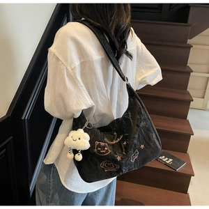 Detail of black embroidered nylon crossbody bag with cat pattern and plush cloud pendant
