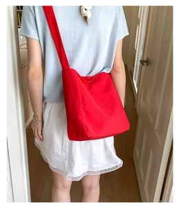 Detailed back view of a red canvas tote bag with a wide shoulder strap for women