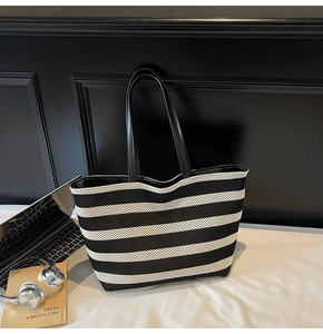 Detail of a large knit tote bag with black and white stripes and leather handles