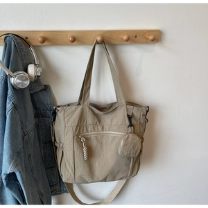 Detail of khaki canvas tote with exterior zip pocket and matching round coin purse charm