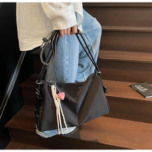 Chic black nylon pillow bag with pink heart pendant shown in a daily lifestyle setting