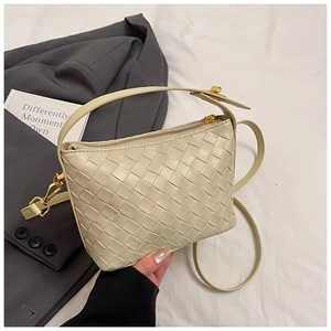 Detail of beige woven leather handbag with gold zipper and adjustable shoulder strap