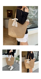 Detail of hand-woven straw tote with white lace bow and brown leather handles