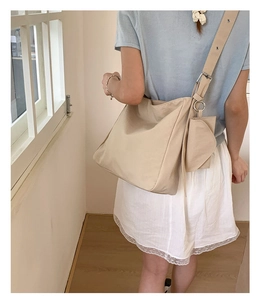 Detail view of large beige canvas hobo bag with adjustable strap and small round pouch