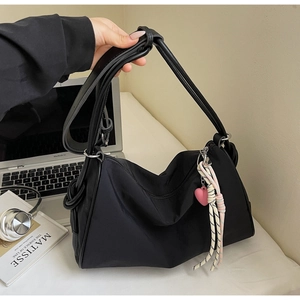 Detail of black nylon pillow bag with pink heart charm and braided rope accessory