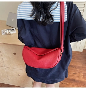 Vue détaillée du sac croissant en cuir rouge à motif litchi avec boucle dorée et bandoulière