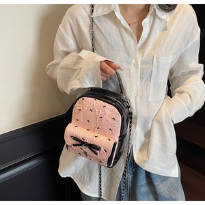 Detail of sweet bow-knot seersucker mini bucket bag with silver chain strap worn by a model