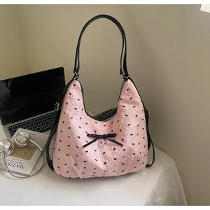 Dettaglio della borsa hobo rosa con motivi a fiocco nero e ciondolo a cuore in metallo