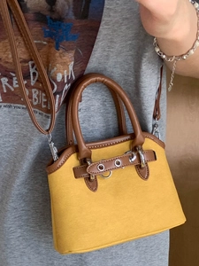 Yellow canvas shell handbag with brown leather trim shown worn as a crossbody bag