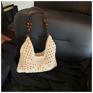 Detail of hand-woven beige shoulder bag featuring floral textures and wooden bead handle