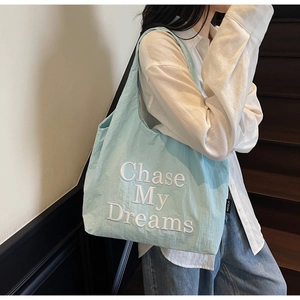 Détail du cabas en toile bleu clair avec broderie Chase My Dreams et étiquette logo
