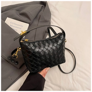 Close-up of black woven shoulder bag with golden zipper and premium leather texture