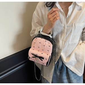 Detail showing pink seersucker mini backpack with black bow prints and heart metal charm