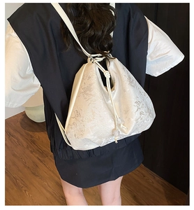 Detail of white jacquard backpack with floral texture, drawstring closure and bead accents