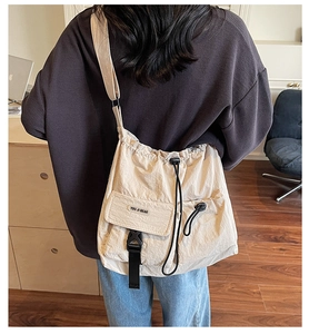 Detail of beige canvas crossbody bag featuring utility flap pocket and drawstring closure