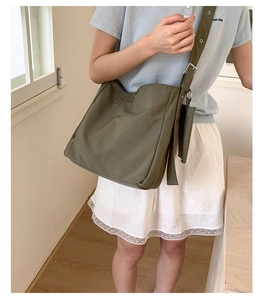 Olive green canvas tote bag shoulder view with adjustable strap and small side pouch