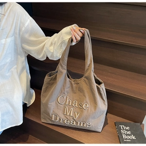 Détail de la broderie Chase My Dreams sur le sac cabas en toile taupe avec lumière douce