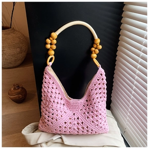 Detail view of pink hand-woven tote bag with decorative wooden bead handles
