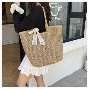 Detail of hand-woven straw tote bag with elegant white lace bow and PU leather handles