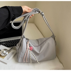Detail of grey minimalist canvas pillow bag with pink heart charm in lifestyle scene