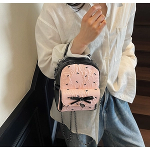 Detail of pink seersucker backpack featuring black bow patterns and silver heart charm