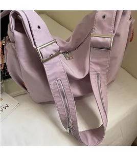 Detail of purple canvas shoulder bag showing adjustable silver buckle and smooth zippers