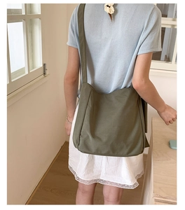 Olive green canvas tote bag worn by model in a minimalist modern interior setting