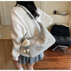 Detail of silver pleated shoulder bag with cat embroidery and a cloud plush pendant