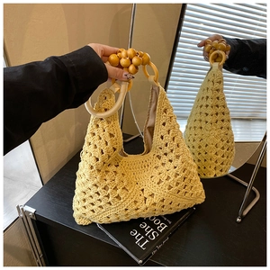 Detail of a yellow crochet hobo bag featuring large wooden bead handles and a woven texture