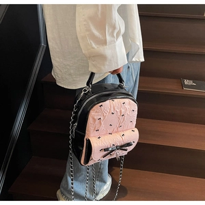 Detailed close-up of a pink seersucker bag with a black bow and silver chain strap