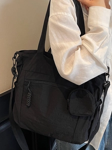 Minimalist black large canvas tote bag with small round coin purse shown on a shoulder