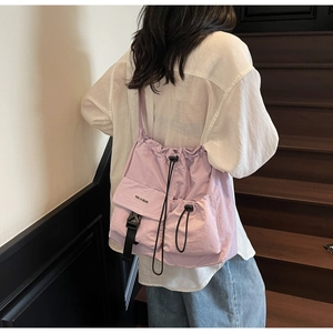 Detail view of the light purple canvas messenger bag with a secure black buckle and drawstring