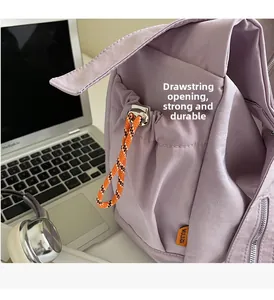 Detail of purple canvas tote bag with orange drawstring closure and brand label