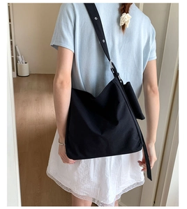 Detail view of a large black canvas tote bag showing the adjustable strap and metal buckle