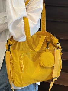 Large yellow nylon tote bag with small round coin purse shown in a casual lifestyle scene